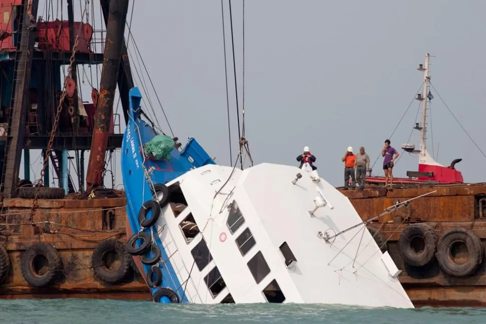 OPERATIVO EN EL MAR. Rescatistas usaron una grúa para sacar el barco hundido. REUTERS