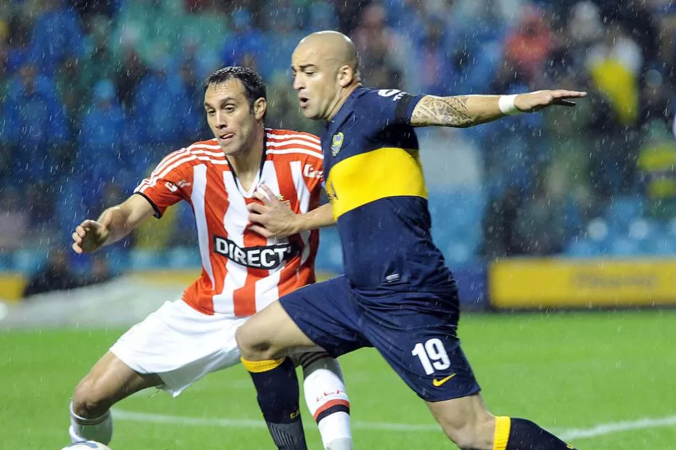 LUCHA. Desábato y Silva forcejean para quedarse con la pelota, en una Bombonera que sufre por la lluvia. TELAM