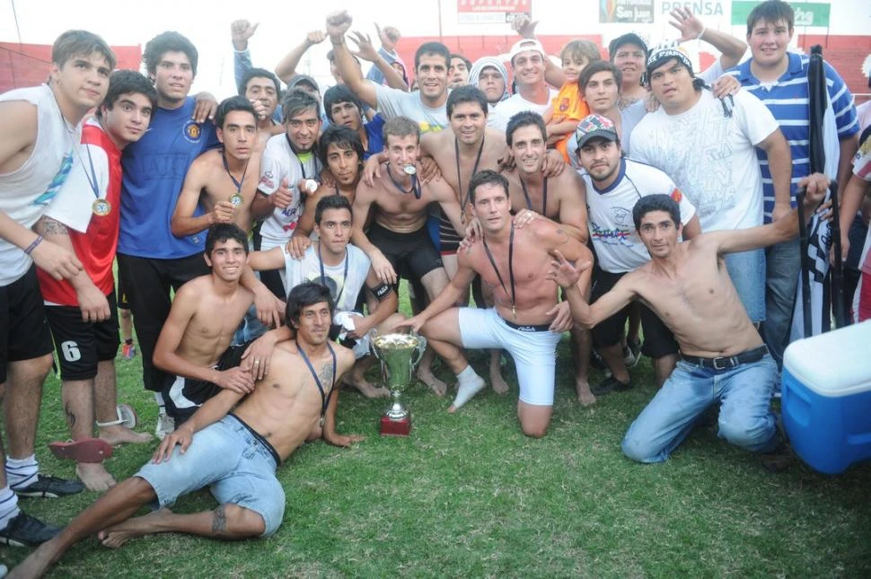 MOMENTO DE GLORIA. Los jugadores del cuervo del este exhiben con orgullo la medalla en el pecho y muestran la copa de campeón del ascenso. Los simpatizantes se unieron a los festejos del plantel. 