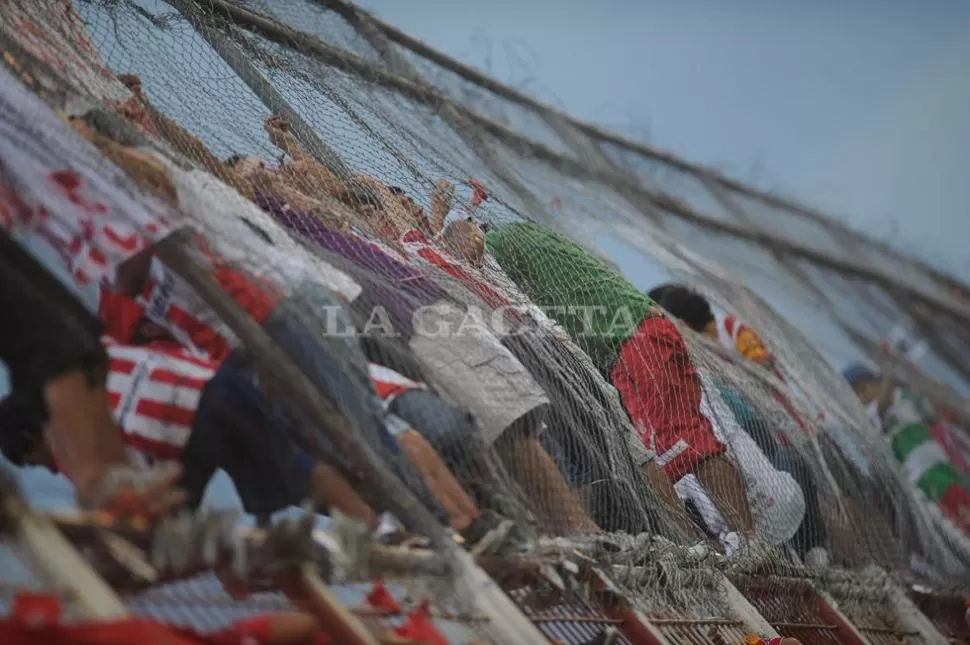 PELIGRO. Muchos hinchas santos tienen la costumbre de mirar el partido desde la cerca parapelotas. LA GACETA / FRANCO VERA 