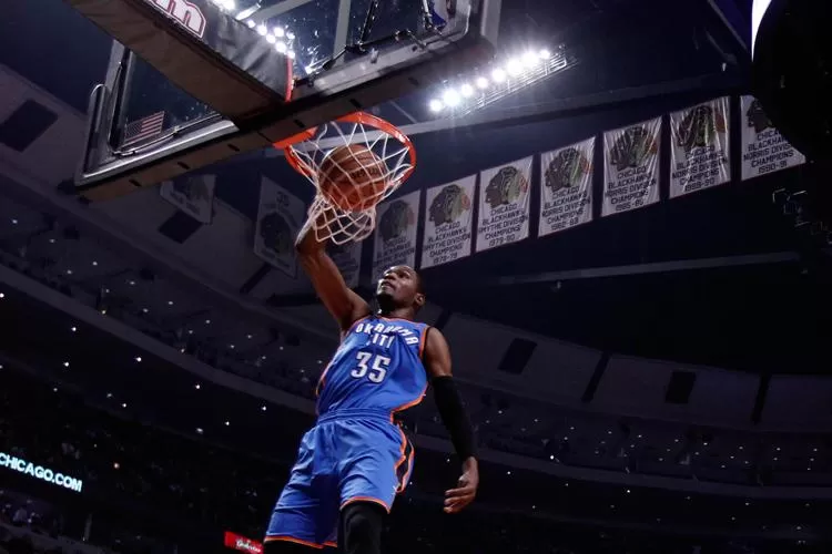 VUELA. Durant vuelca la pelota ante la mirada del base Marco Belinelli. REUTERS