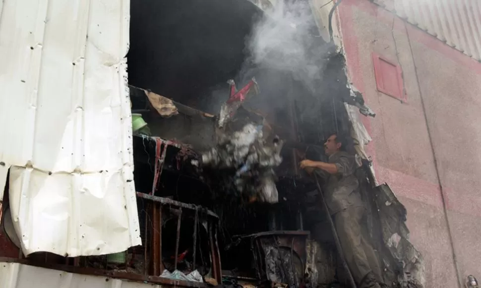 SALDO DE LA VIOLENCIA. Un habitante palestino trata de apagar el incendio que dejaron en su casa las bombas de tanques israelíes. REUTERS 