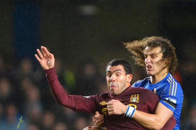 LUCHADO. El argentino Carlos Tevez sufre el rigor de la marca del portugués David Luiz. REUTERS