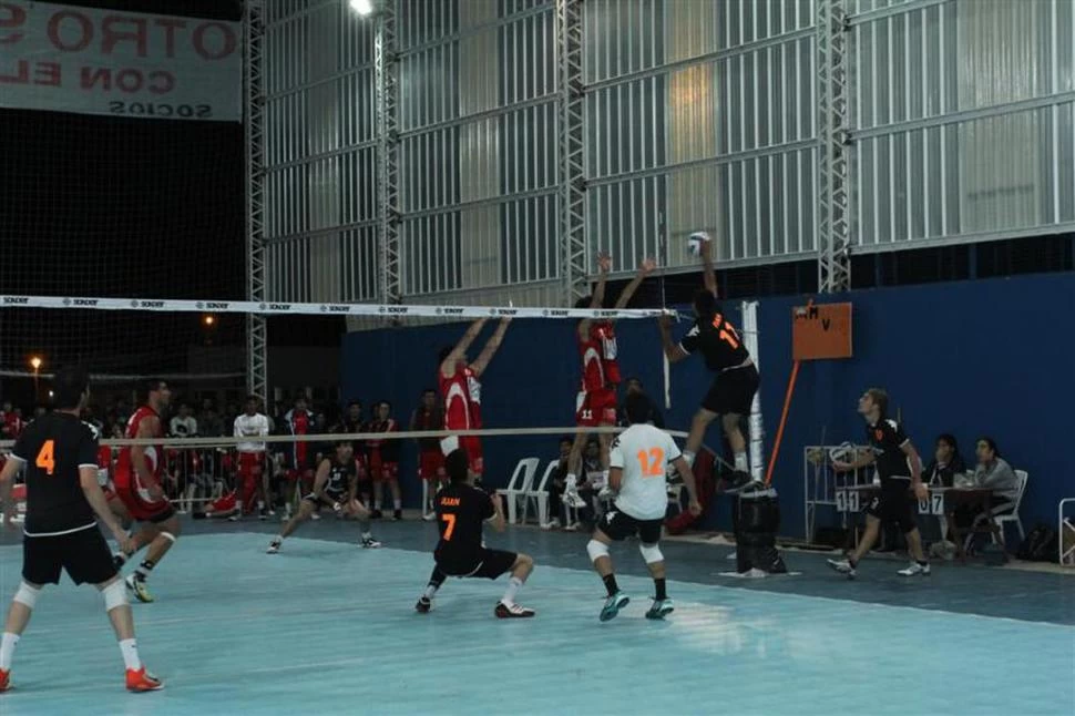 BIEN ALTO. Iván López impacta la pelota en el aire ante el doble bloqueo de Social. 