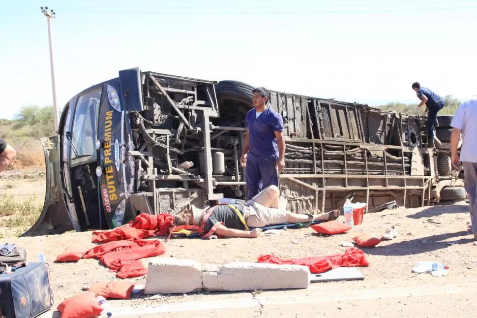 VOLCADO. El colectivo cayó al intentar esquivar al camión y entre los propios pasajeros lograron sacar a los que estaban más graves y apenas podían moverse. En la foto, una de las víctimas es asistida por el servicio de emergencias. FOTOS GENTILEZA DIARIO EL ZONDA Y DIARIO DE CUYO