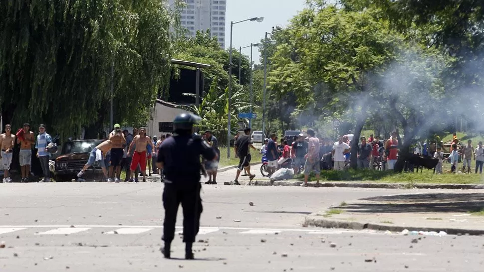 JORNADA VIOLENTA. Un policía enfrenta a los grupos que intentaban entrar a un supermercado. REUTERS