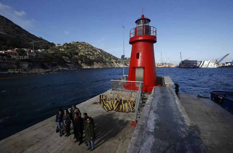 RECUERDO DOLOROSO. Familiares de las víctimas estuvieron ayer en el faro de Giglio. Al fondo se ve el crucero. REUTERS