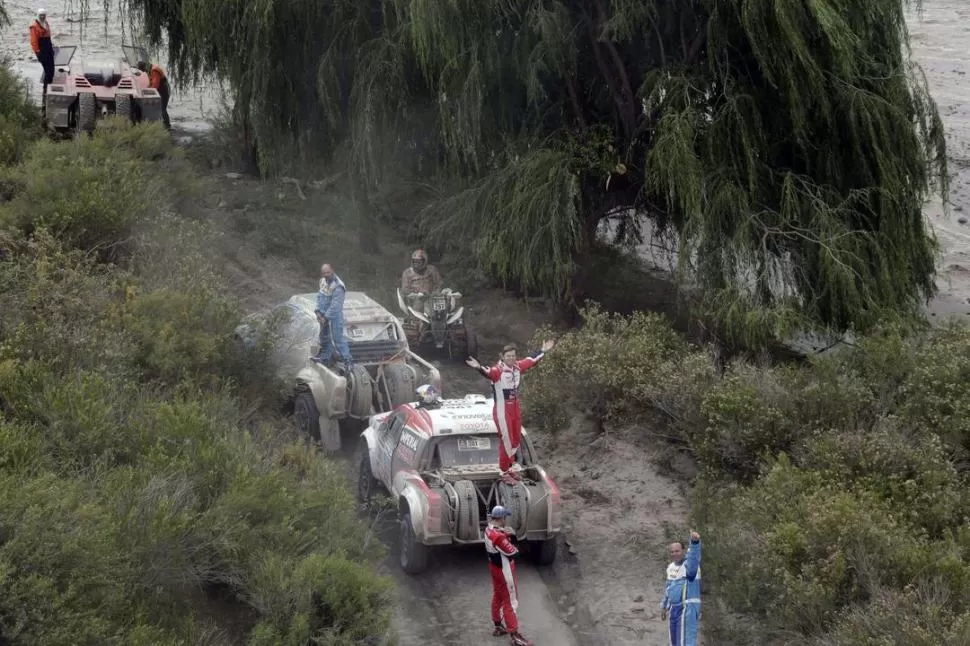 AL MAL TIEMPO, BUENA CARA Y UN POCO DE PACIENCIA. Un grupo de pilotos y asistentes saluda a la cámara del helicóptero mientras espera para poder avanzar por los fangales que dejó la lluvia en los valles. 