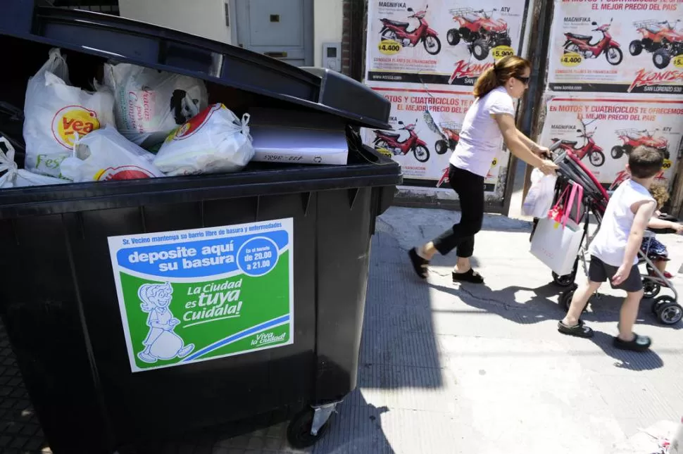 A LA ESPERA DEL RECOLECTOR. Una mujer que empujaba un coche pasa por detrás del contenedor de Junín, casi Santa Fe; repleto de bolsas de la cuadra, aguarda el paso de los basureros. 