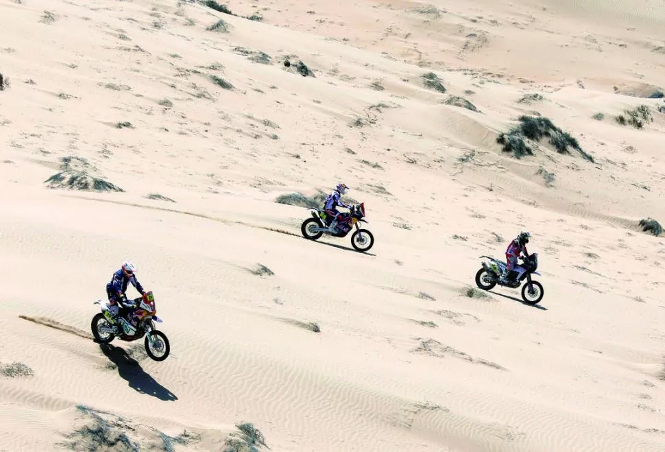 TODOS POR LO MISMO. Tres pilotos y sus motos, lanzados a plena velocidad, en una zona arenosa en pendiente. La pericia al manejo es principal aliada de todos. 