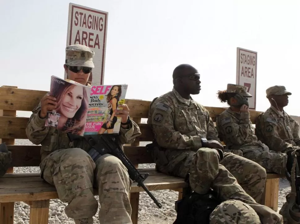 EN ESPERA. Una mujer soldado lee una revista, mientras aguarda un traslado. REUTERS