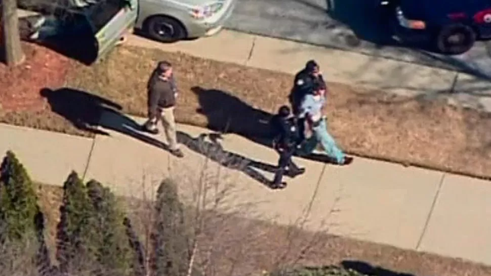 ESPOSADO. Un sospechoso es escoltado por la policía en las inmediaciones de la Price Middle School. REUTERS