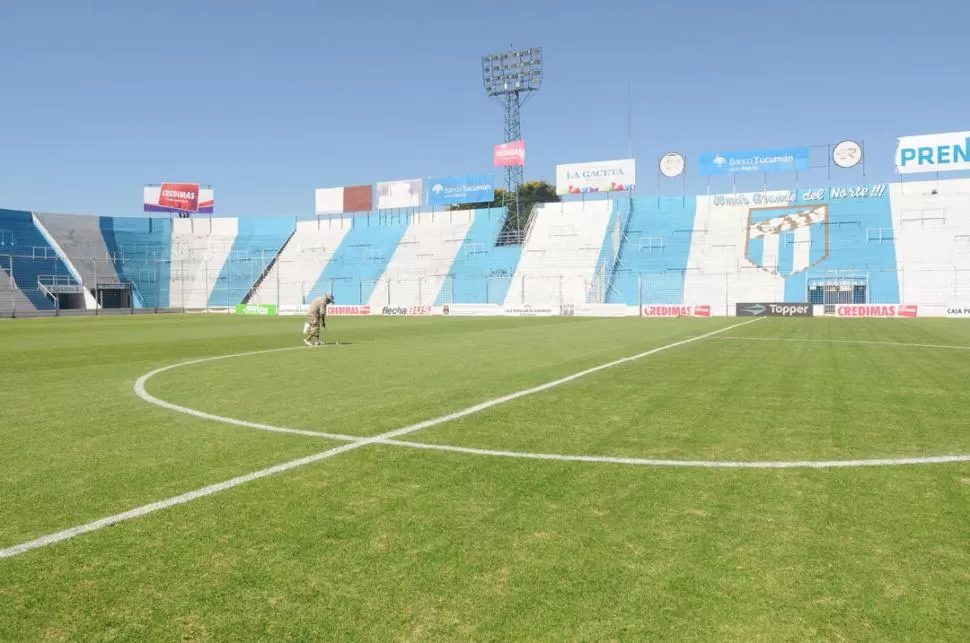 LISTO PARA RECIBIR UNA MULTITUD. Un operario de Atlético pinta las líneas del campo. En el fondo, se puede observar la verja que se instaló para separar a las dos hinchadas, cerca de la mitad de la cancha. 