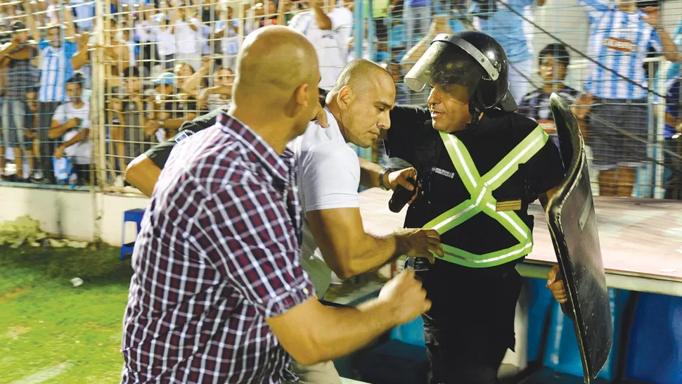 ¡MARCHE PRESO! El policía (con remera blanca), que prestaba servicio para Atlético, es llevado por dos colegas luego de que un uniformado le quitara el arma. Está detenido y a disposición de la Justicia. LA GACETA / FOTO DE JORGE OLMOS SGROSSO