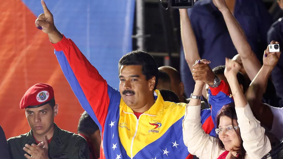 CELEBRACIÓN POR ANTICIPADO. El candidato oficialista, luego de sufragar, saluda a los militantes chavistas que se acercaron a vivarlo y acompañarlo. REUTERS