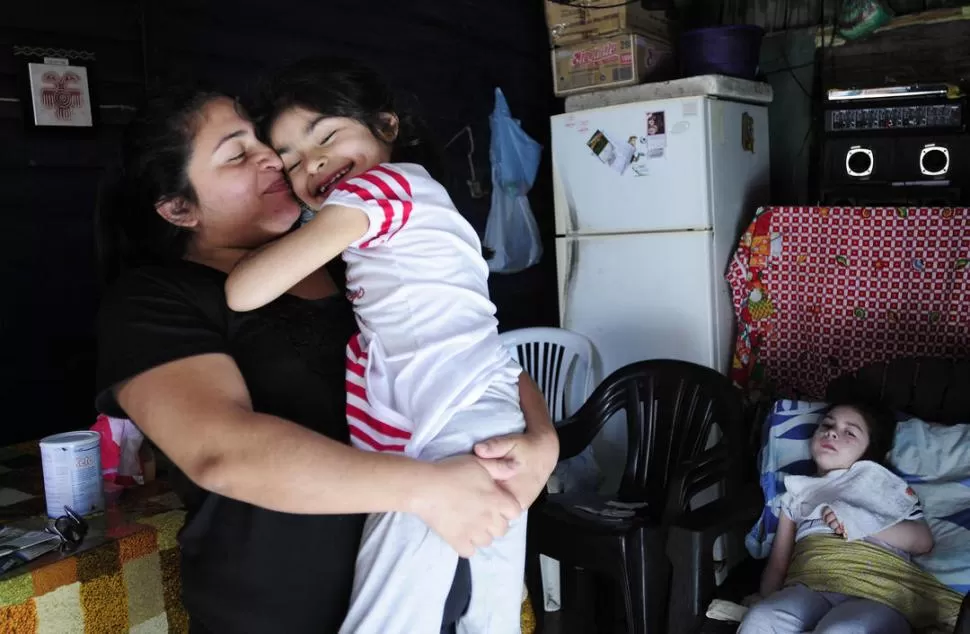 JUNTAS. Carolina es inquieta y cariñosa, siempre recibe con una sonrisa a las visitas aunque no habla. Valentina (atrás) apenas mueve la cabeza. LA GACETA / FOTO DE ANALIA JARAMILLO 