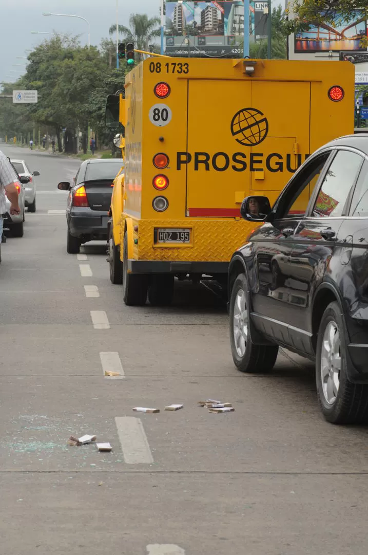 RASTROS. Los fajos de $ 100 y los vidrios rotos en el pavimento. FOTOS LA GACETA