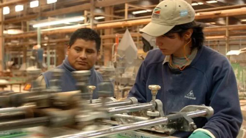 EN MARCHA. Jóvenes trabajan en una de las fábricas recuperadas. TELAM