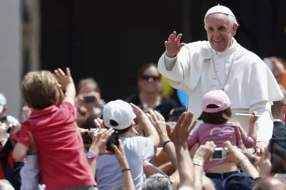 DISTENDIDO. Los niños saludan con cariño a Francisco, mientras lo ven pasar. REUTERS 