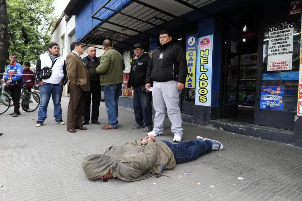 EN MEDIO DE LOS CURIOSOS. En la vereda y rodeado por policías de civil, el delincuente fue esposado y luego trasladado a una celda.  LA GACETA / FOTO DE JORGE OLMOS SGROSSO