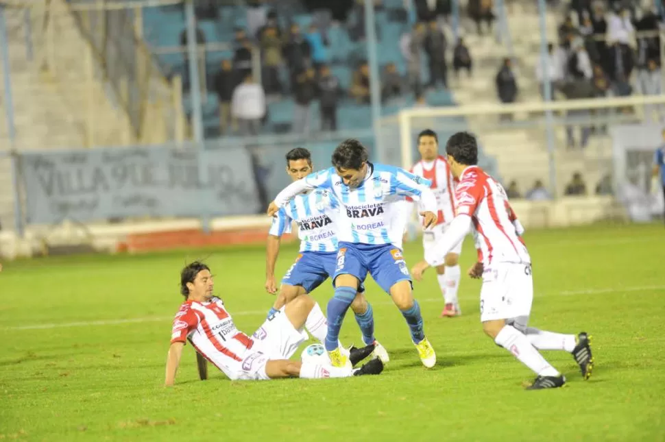 DURA PELEA. Diego Barrado pelea la pelota con un rival. Matías Ballini observa atentamente el desenlace de la jugada. 