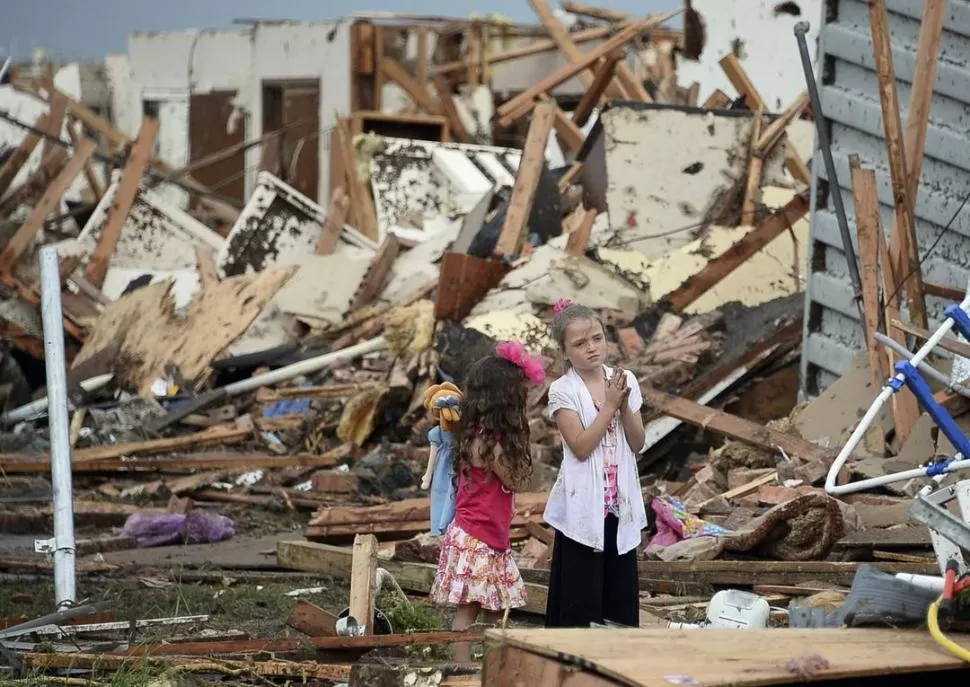 PLEGARIA. Una niña reza frente a los restos de lo que fue su vivienda.  