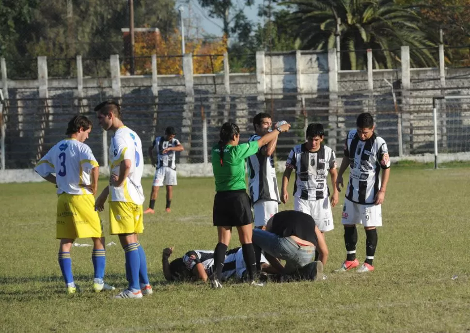 DOLOR. Robles es asistido en el campo de juego luego de sufrir la lesión.  