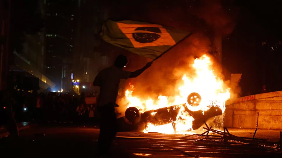 DESCONTROL. Un auto terminó en llamas en medio de la protesta. REUTERS