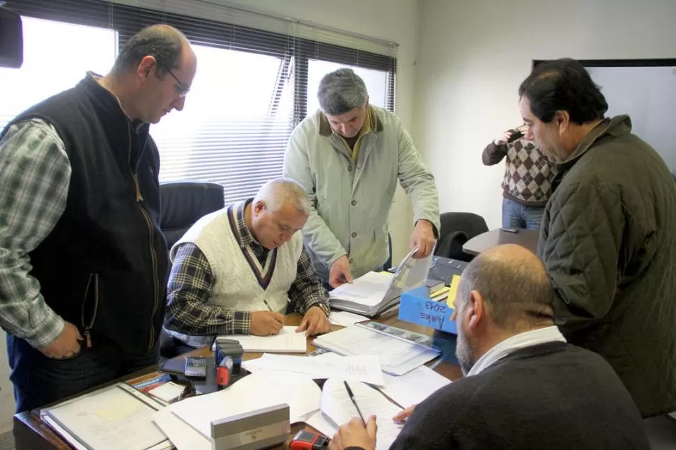 EN EL PJ. Sergio Arroyo arma los papeles de la lista alperovichista. Marcelo Caponio (a su derecha) y Sergio Mansilla (frente a Arroyo) observan con atención. PRENSA Y DIFUSION  