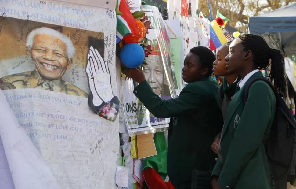 OFRENDAS. Miles de personas pasan por el hospital donde está Mandela. REUTERS