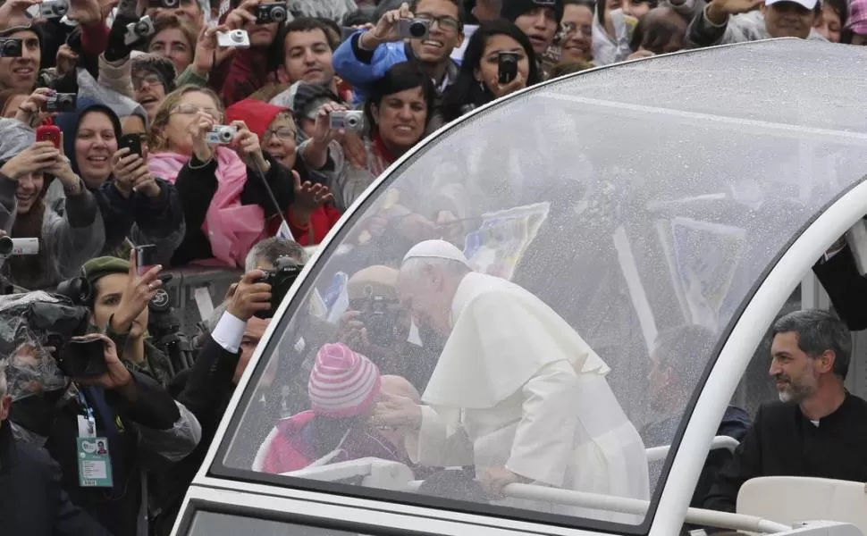 SALUDO A UNA NIÑA. Ya se hizo habitual: Francisco hace detener el papamóvil para saludar a los chicos. Ayer ocurrió en Aparecida. FOTOS DE EFE-REUTERS