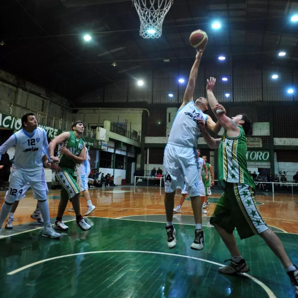 REBOTE DEFENSIVO. Rubén Valdez, de Tucumán BB, se apoderó del balón, pese al intento de Patricio Castagnaro. 