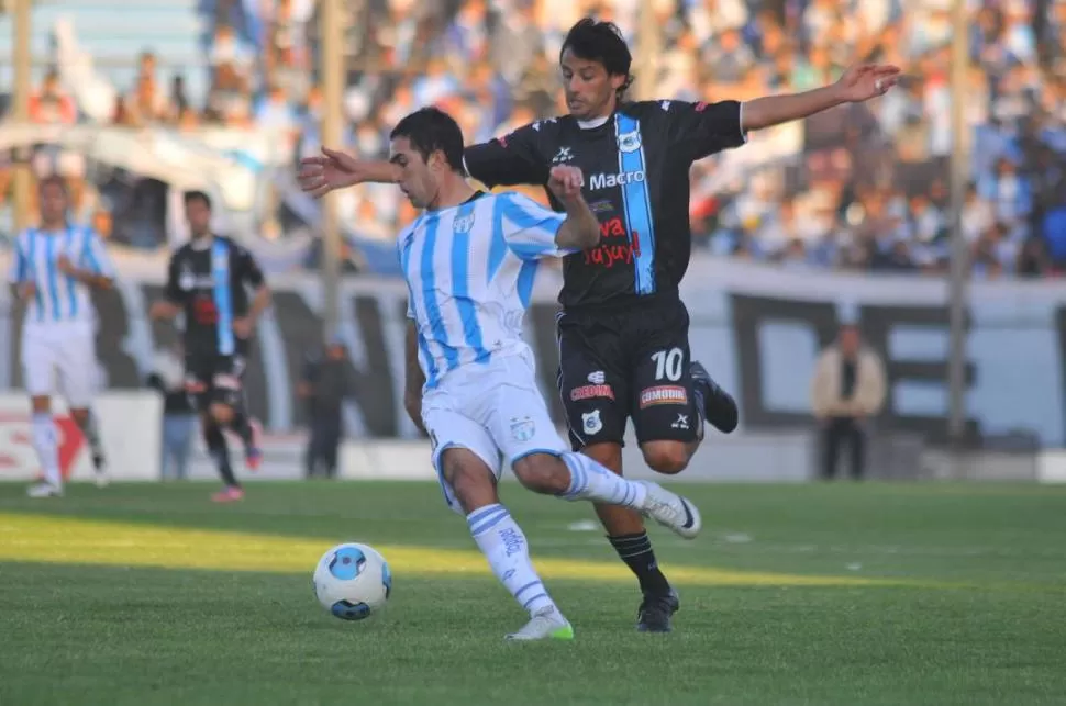 DUELO DE NÚMEROS 10. Canever, de flojo partido, protege la pelota ante Gabriel Bustos, que trató de conducir al lobo. 