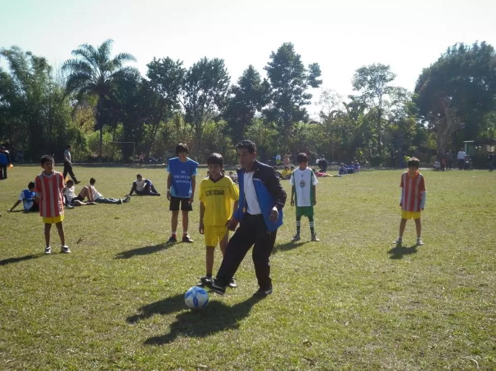 ENSEÑAR ES LO MAS LINDO. Hugo Juárez le pega a la pelota ante la atenta mirada de los chicos.  