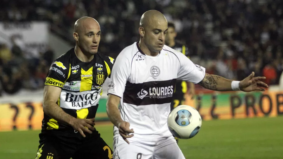 DUELO DE PELADOS. Santiago Silva, de Lanús, se adelanta con la pelota al defensor Iván Furios, de Olimpo. DYN