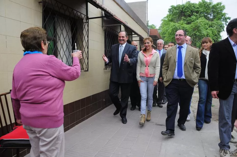 CAMINANDO EL CIRCUITO 20. El gobernador Alperovich recibirá un mate de una vecina. Caponio los observa. PRENSA Y DIFUSION