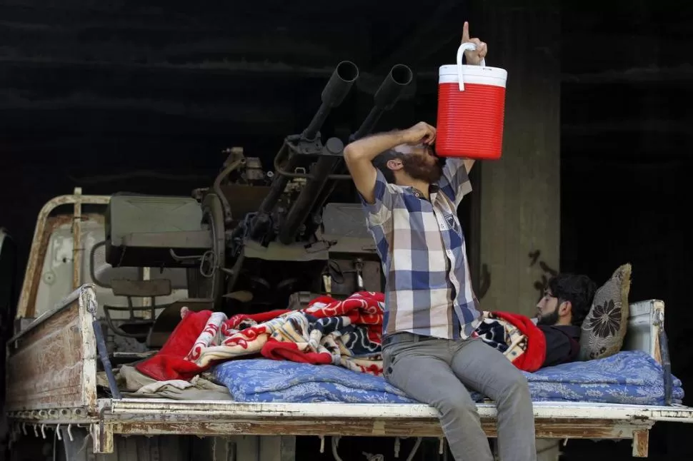 EN DESCANSO. Dos combatientes del opositor Ejército Libre Sirio están a cargo de una batería antiaérea. REUTERS