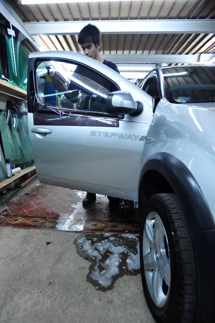 PROCESO. Un técnico coloca un film oscuro en una ventanilla. 