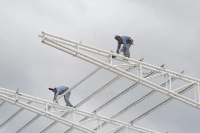 Sin arneses, los obreros avanzan sobre el techo del estadio