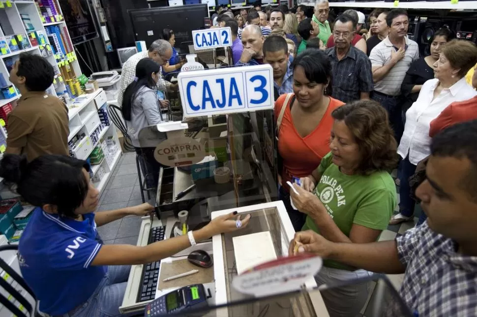 CONTROL. Consumidores caraqueños hacen cola en un supermercado. REUTERS