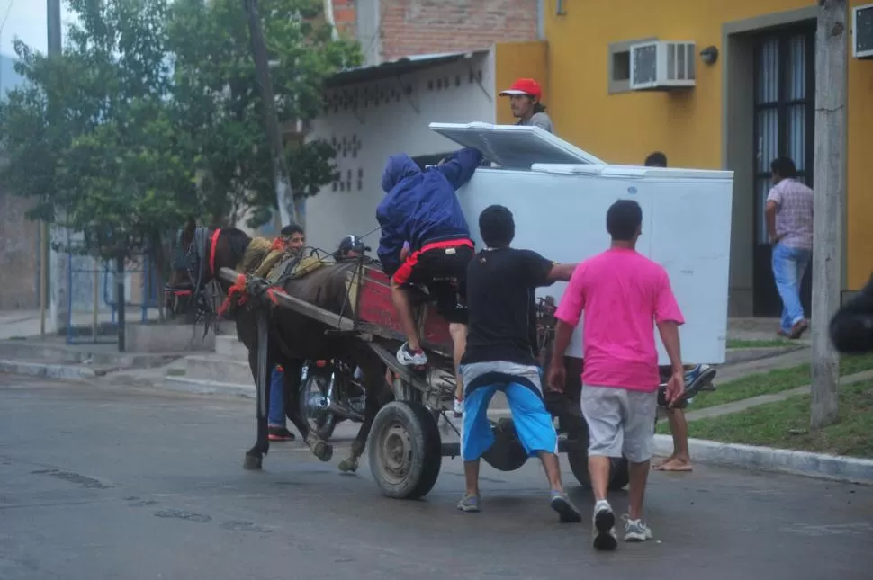 HASTA EL FREZZER. En Ejército del Norte al 2.300 desvalijaron una heladería, en la imagen se ve cómo los saqueadores -que circulaban en moto- suben un frezzer a un carro que hicieron parar; después subieron a sus motos y huyeron. la gaceta / fotos de diego aráoz