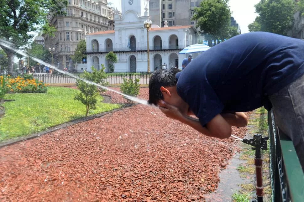 EN EL HORNO. Los porteños tratan de refrescarse en plena Plaza de Mayo, frente al Cabildo, de la ola de calor que afecta los servicios de agua y de luz. telam