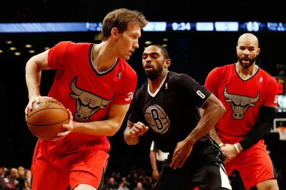 TODOS DE ESTRENO. Dunleavy, de los Chicago Bulls, lleva la pelota ante la marca de Anderson, de Brooklyn Nets, y la cortina de Boozer. Los jugadores estrenaron las camisetas mangas cortas. 