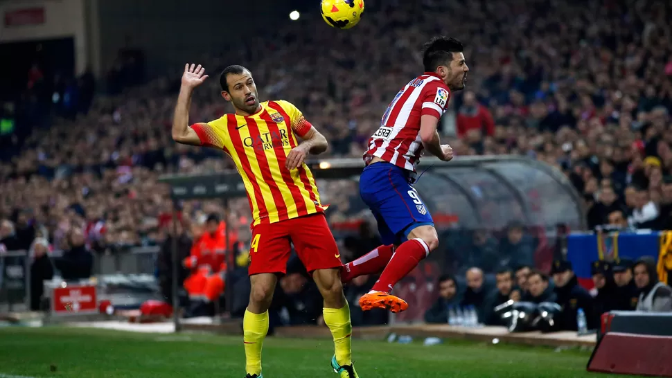 EN EL AIRE. Mascherano disputa una pelota con Villa. REUTERS