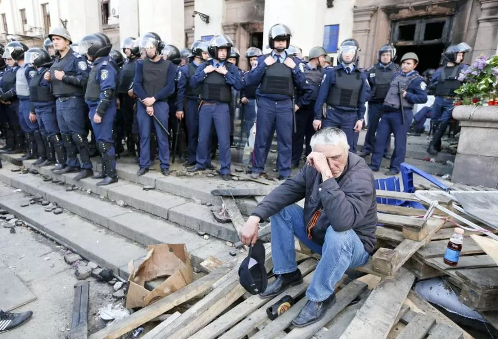 EN ODESSA. Un activista prorruso llora por la muerte de muchos de sus compañeros en el edificio sindical incendiado, ahora custodiado por policías. reuters