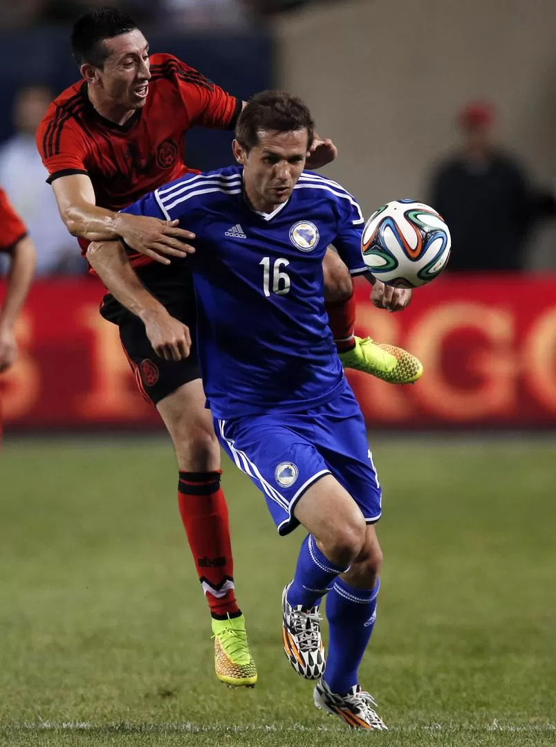 MUCHA LUCHA. Senad Lulic, de Bosnia, disputa el balón ante la marca de Héctor Herrera en el cotejo jugado en Chicago. REUTERS