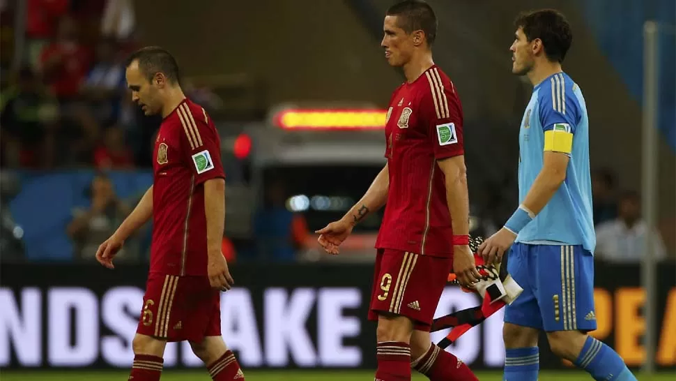 ELIMINADOS. Iniesta, Torres y Casillas se retiran de la cancha con las cabezas bajas y toda la decepción a cuesta. Los campeones quedaron eliminados. REUTERS