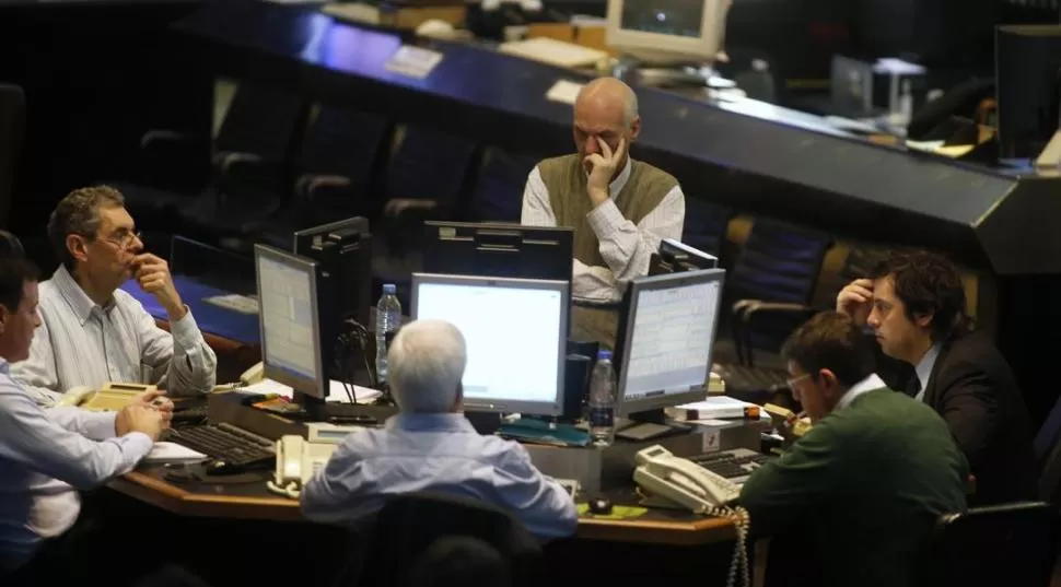 GESTOS ADUSTOS. Agentes de la Bolsa porteña miran en sus pantallas los altibajos de las cotizaciones de bonos y acciones, entre dudas y temores. reuters