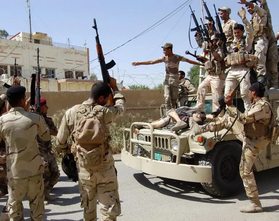 CERCA DE SAMARRA. Tropas del Ejército celebran sobre el cadáver de un yihadista, la toma de una posición. reuters