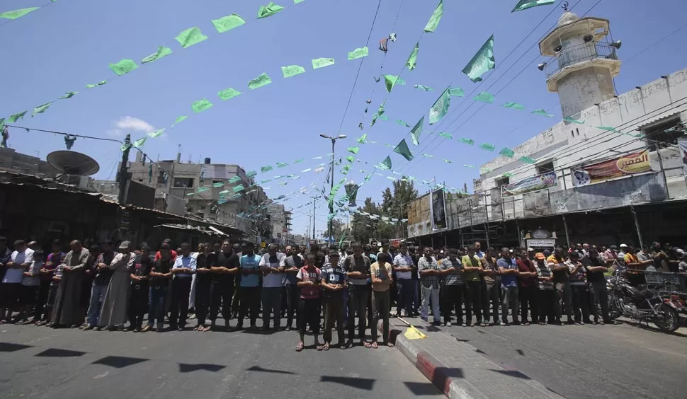 PLEGARIAS. A las puertas de una mezquita, los deudos ofrecen homenaje a tres jóvenes palestinos muertos durante un bombardeo en Rafah. REUTERS